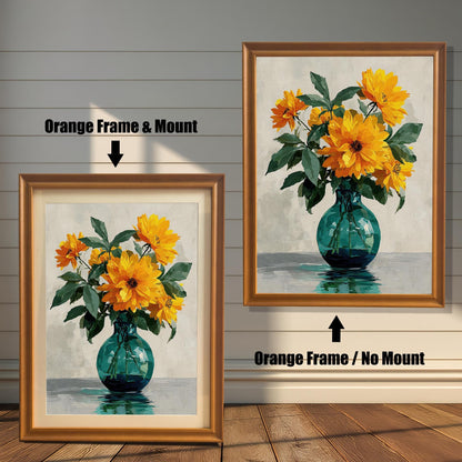 Two framed art prints of yellow flowers in a green vase on a wooden floor. The print on the left is in an orange frame with a mount, and the one on the right is in an orange frame without a mount.