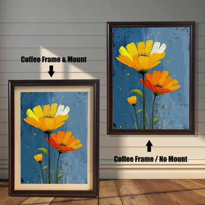 Two framed art prints of yellow and orange flowers on a wooden floor. The print on the left is in a coffee-colored frame with a mount, and the one on the right is in a coffee-colored frame without a mount.