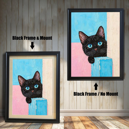 Two framed prints of a black cat with blue eyes on a wood paneled wall. One has a black frame with a mount, and the other is a black frame without a mount.