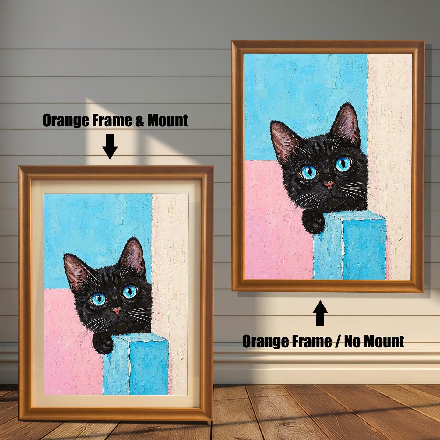 Two framed prints of a black cat with blue eyes on a wood paneled wall. One has an orange frame with a mount, and the other is the same frame without a mount.