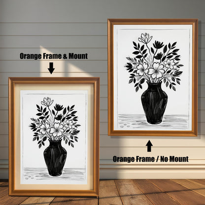 A black and white drawing of flowers, shown in two orange-brown frames. The one on the left includes a light mount, while the one on the right hangs on the wall without a mount.