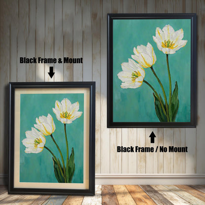 A framed art print of three white tulips, showing two options: one in a black frame with a tan mat and one in a black frame without a mat. The background is a vertical wooden wall.