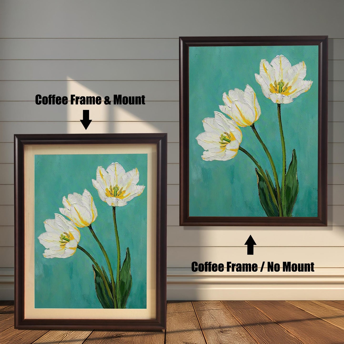 A framed art print of three white tulips. One is in a coffee-colored frame with a tan mat, and the other is in the same frame without a mat. The art is against a white wooden wall.