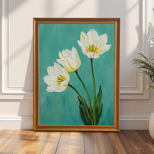 A framed art print of three white tulips with green leaves on a teal background. The print is in an orange-brown frame, leaning against a white wainscoting wall next to a potted snake plant.