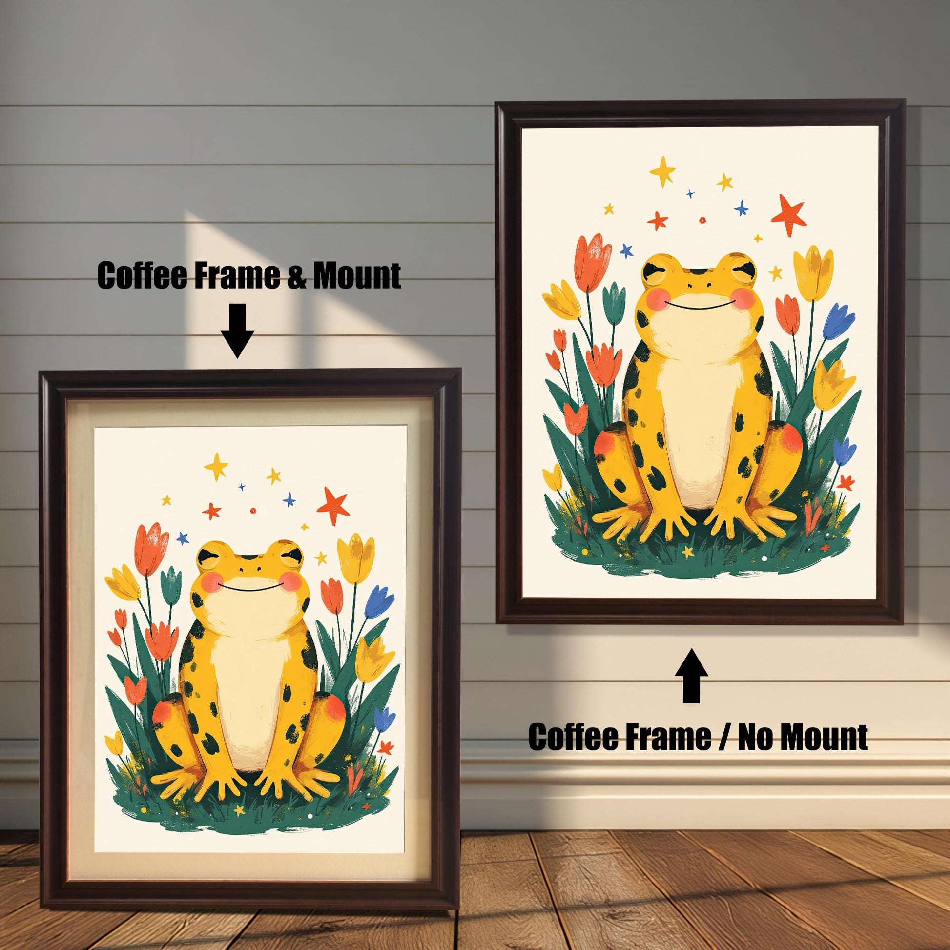 Two versions of a happy yellow frog wall art print with a coffee-colored wood frame. The print on the left is a smaller size framed with a white mount (or mat), and the one on the right is a larger size without a mount. The image shows the framed print hanging against a white paneled wall.