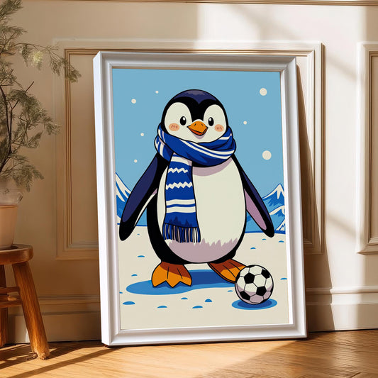 A white-framed print of a cartoon penguin playing soccer in a snowy landscape leaning against a wall, with a small potted plant on a wooden stool in the left corner.