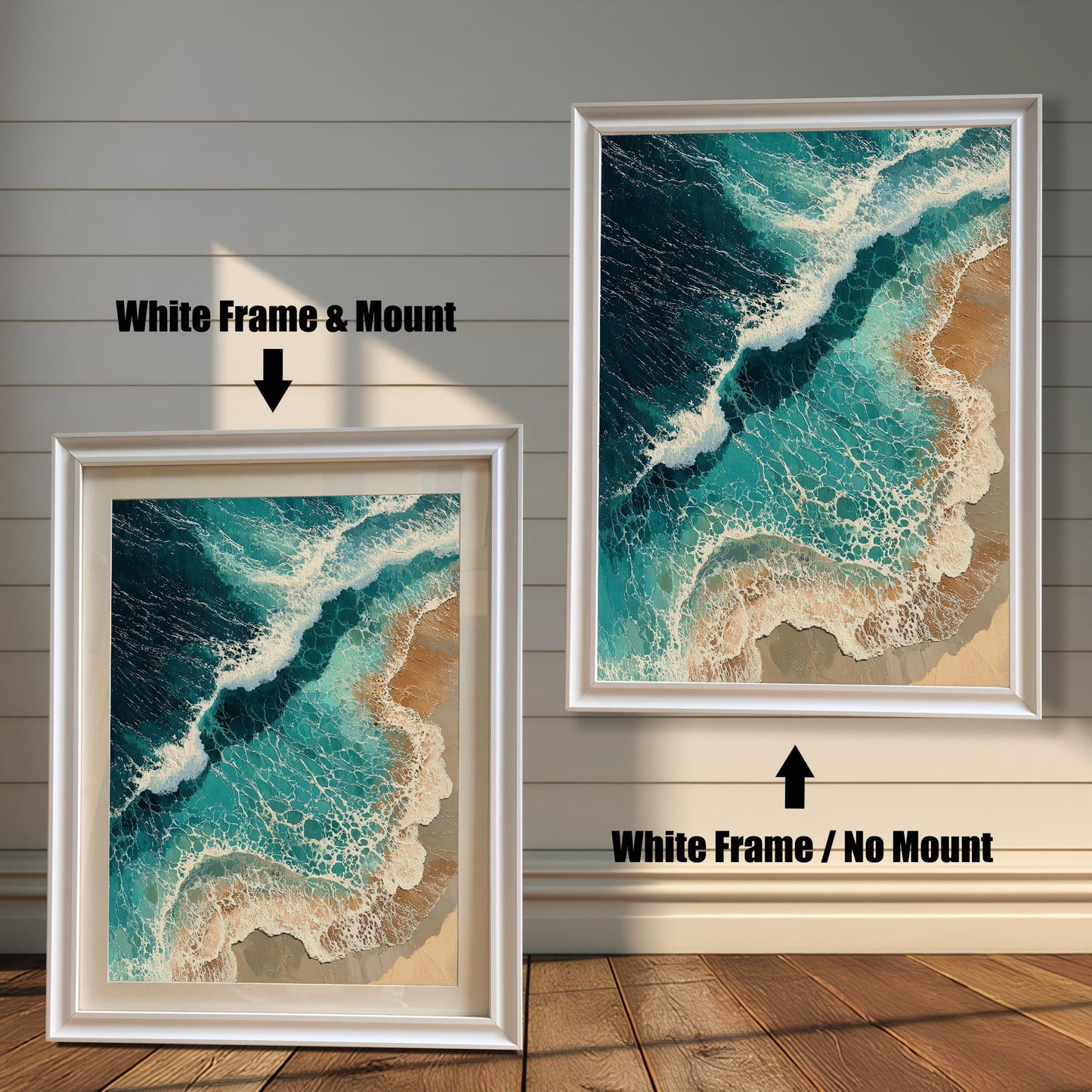 Two framed art prints are displayed against a wall with wainscoting. The one on the left has a white frame with a mount, and the one on the right has a white frame with no mount. The print is an aerial view of waves on a beach.