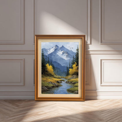 A gold-framed art print of a mountain landscape with a stream and yellow trees leans against a white paneled wall.