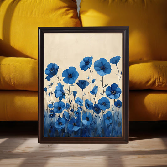 A framed art print of blue flowers with a light background. The dark brown-framed art is propped on a wooden floor in front of a yellow couch.