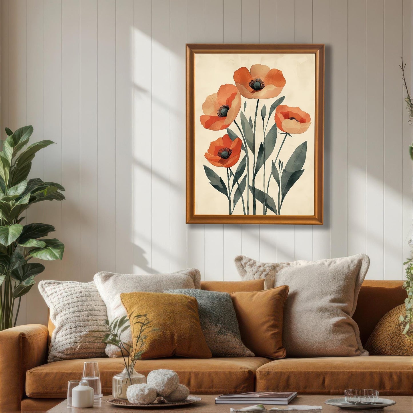 A framed art print of five orange poppies on a pale background, with a gold frame, hanging on a white wainscoting wall above a brown couch.