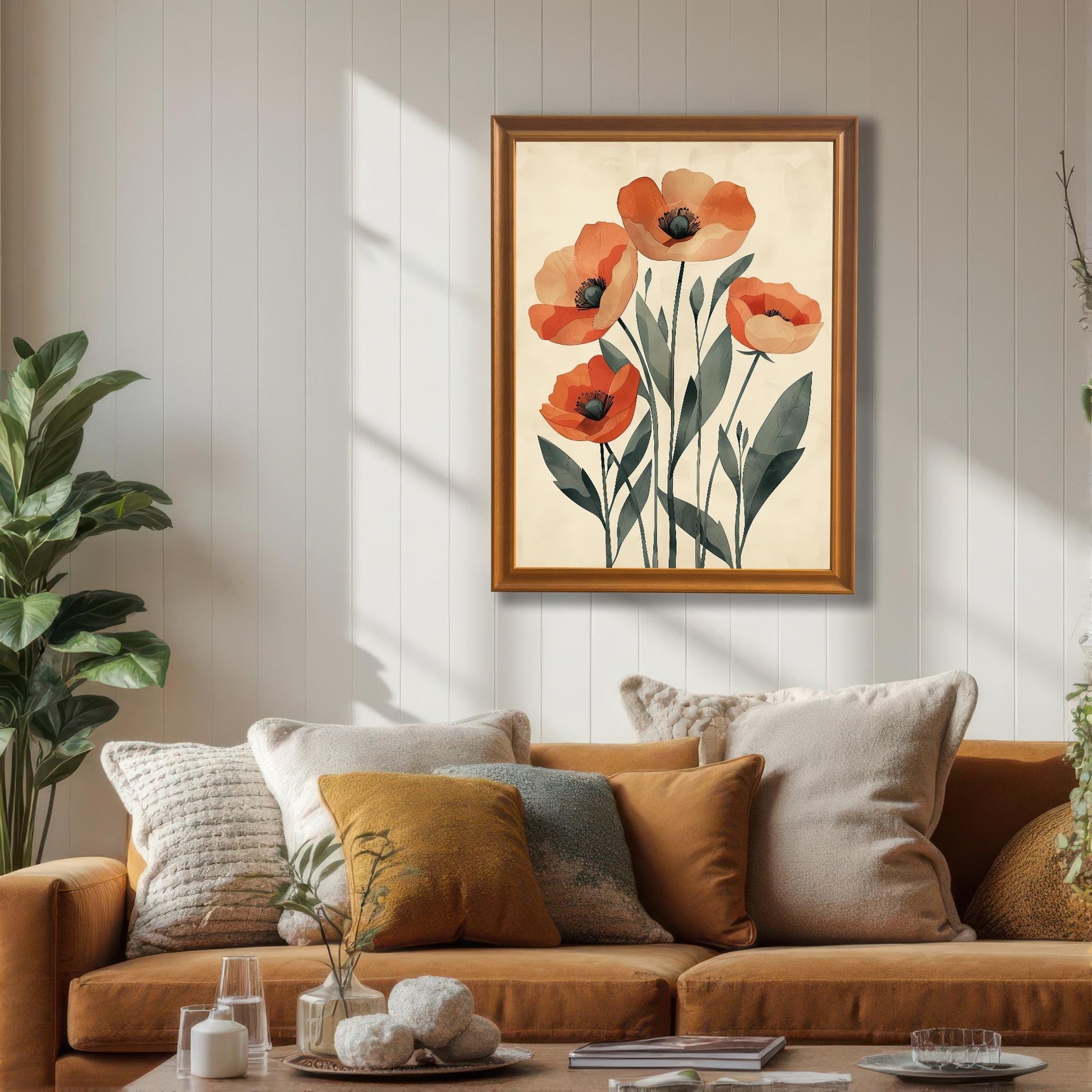 A framed art print of five orange poppies on a pale background, with a gold frame, hanging on a white wainscoting wall above a brown couch.