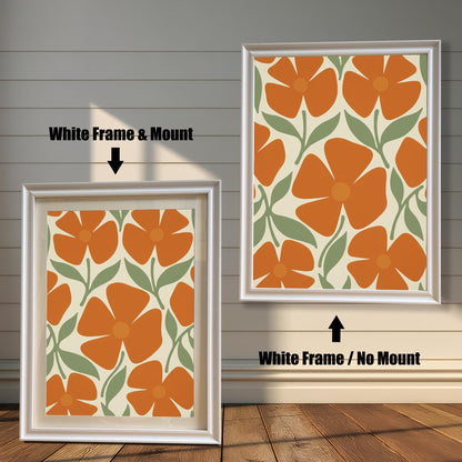 Two white-framed art prints with a repeating pattern of orange flowers and green leaves. One has a white mat board and the other does not.