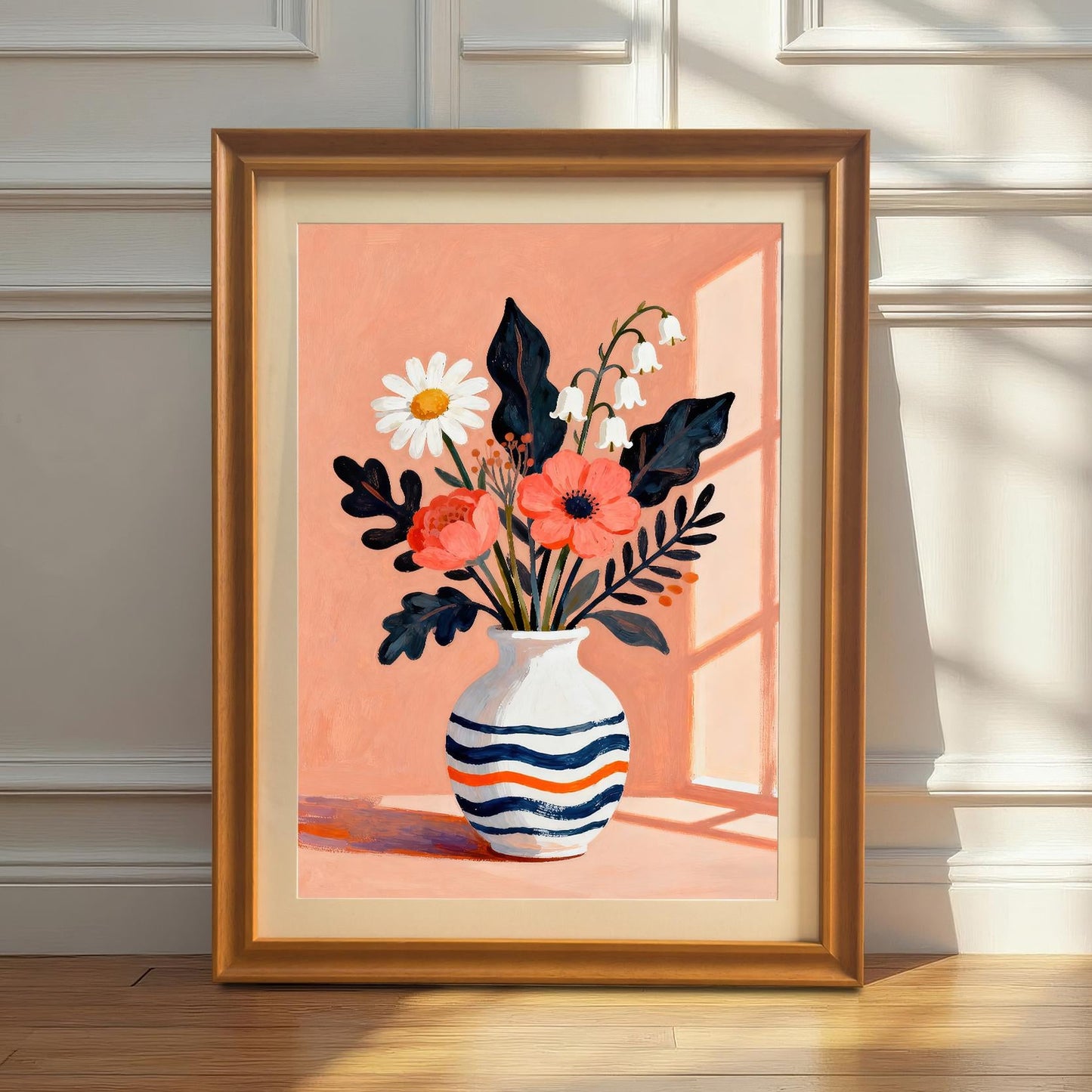 A framed art print featuring a vase of flowers with a light orange background. The print is leaning against a white wainscoted wall on a hardwood floor, with sunlight casting a shadow.