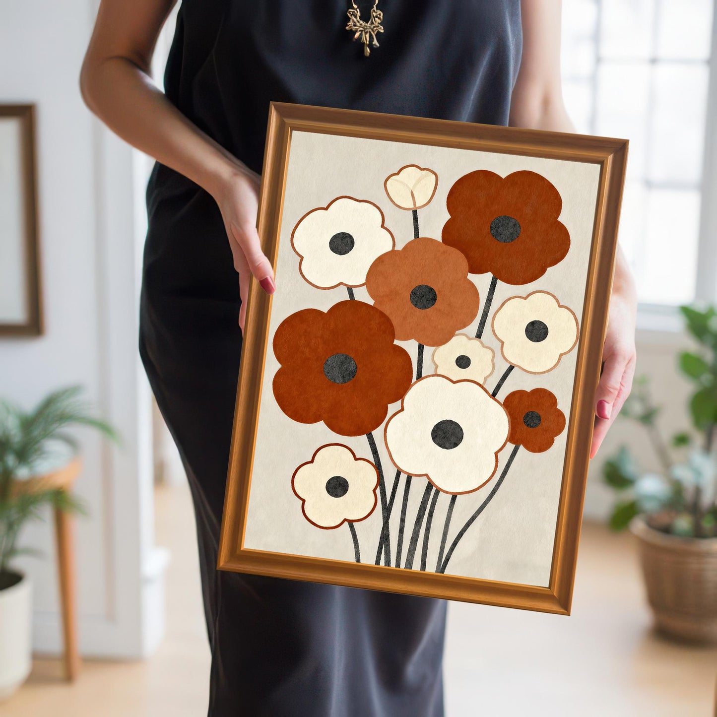 A woman in a black dress holds a framed abstract floral painting with brown and white flowers.
