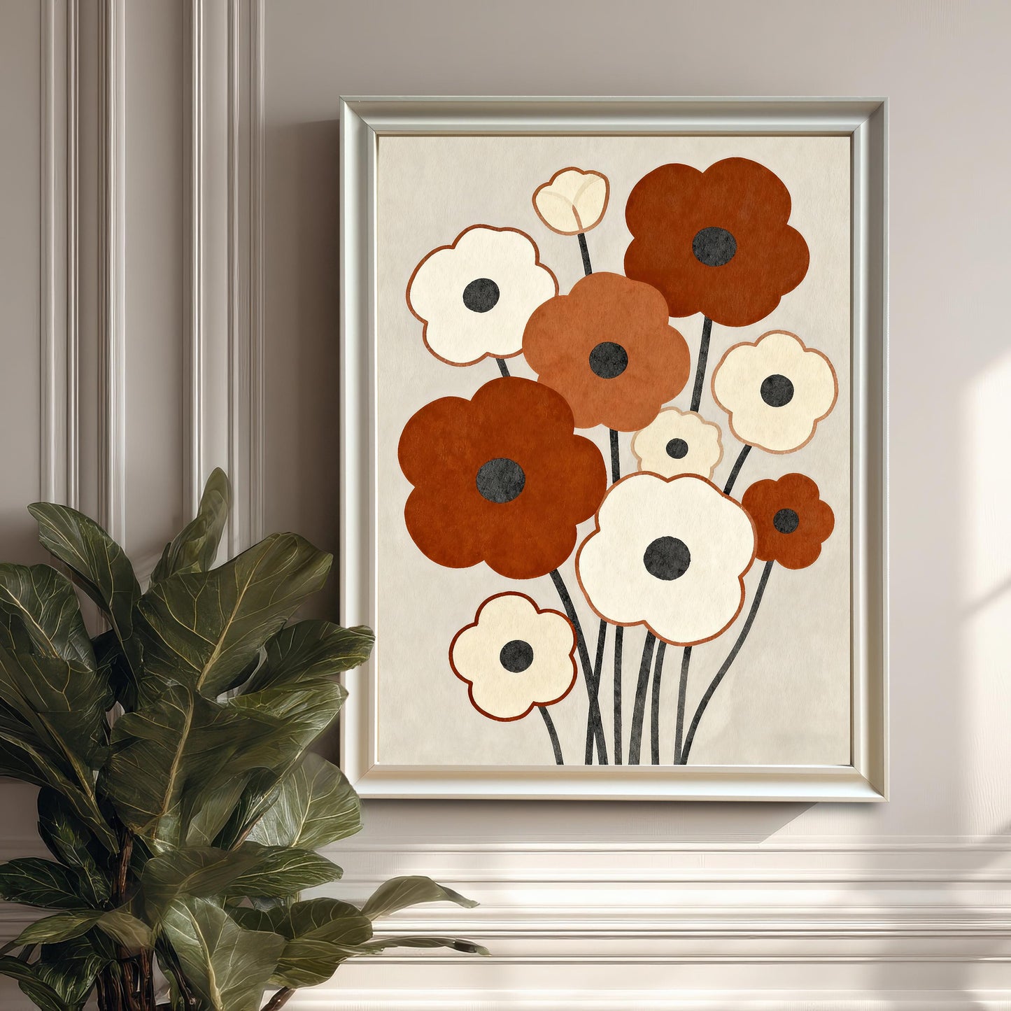 An abstract floral painting with brown and white flowers in a silver-colored frame hangs on a paneled white wall next to a large potted plant.