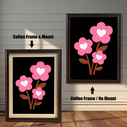 A framed art print of three pink flowers with white hearts is shown in two styles against a wooden wall. One has a coffee-colored frame with a white mount, the other is a larger size with the same frame, but no mount.