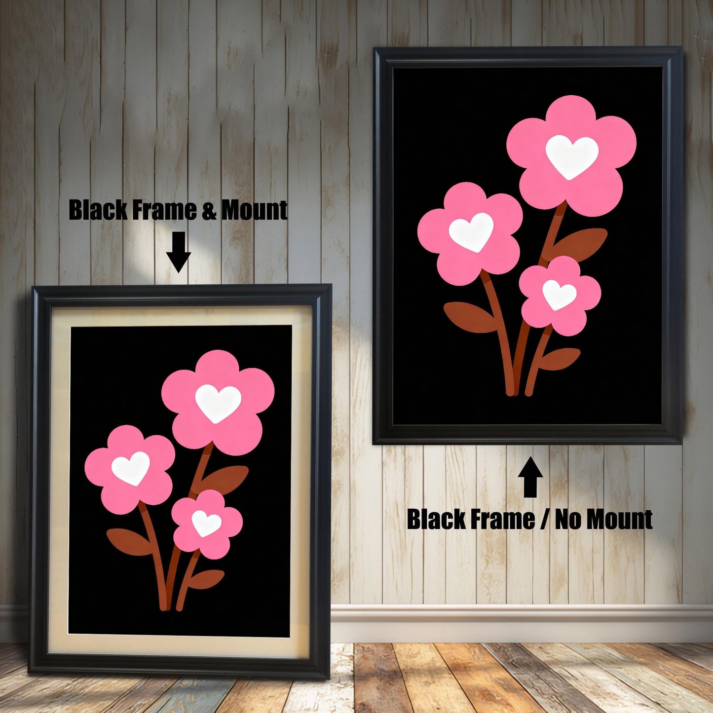 A framed art print of three pink flowers with white hearts is shown in two styles against a wooden wall. One has a black frame with a white mount, the other is a larger size with the same frame, but no mount.