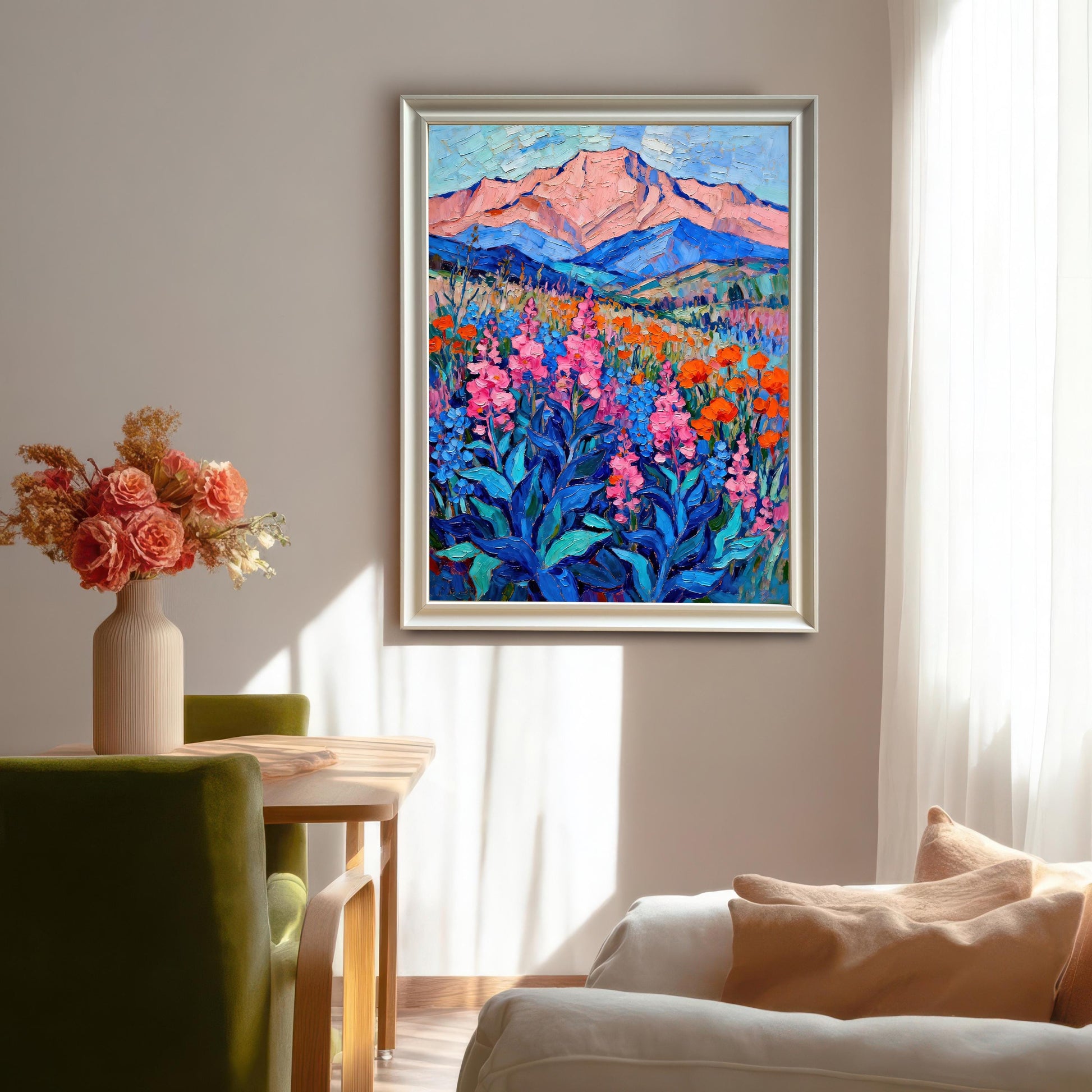 A framed oil painting of a vibrant mountain landscape hangs on a white wall in a dining area. The white frame complements the room's decor and furniture.