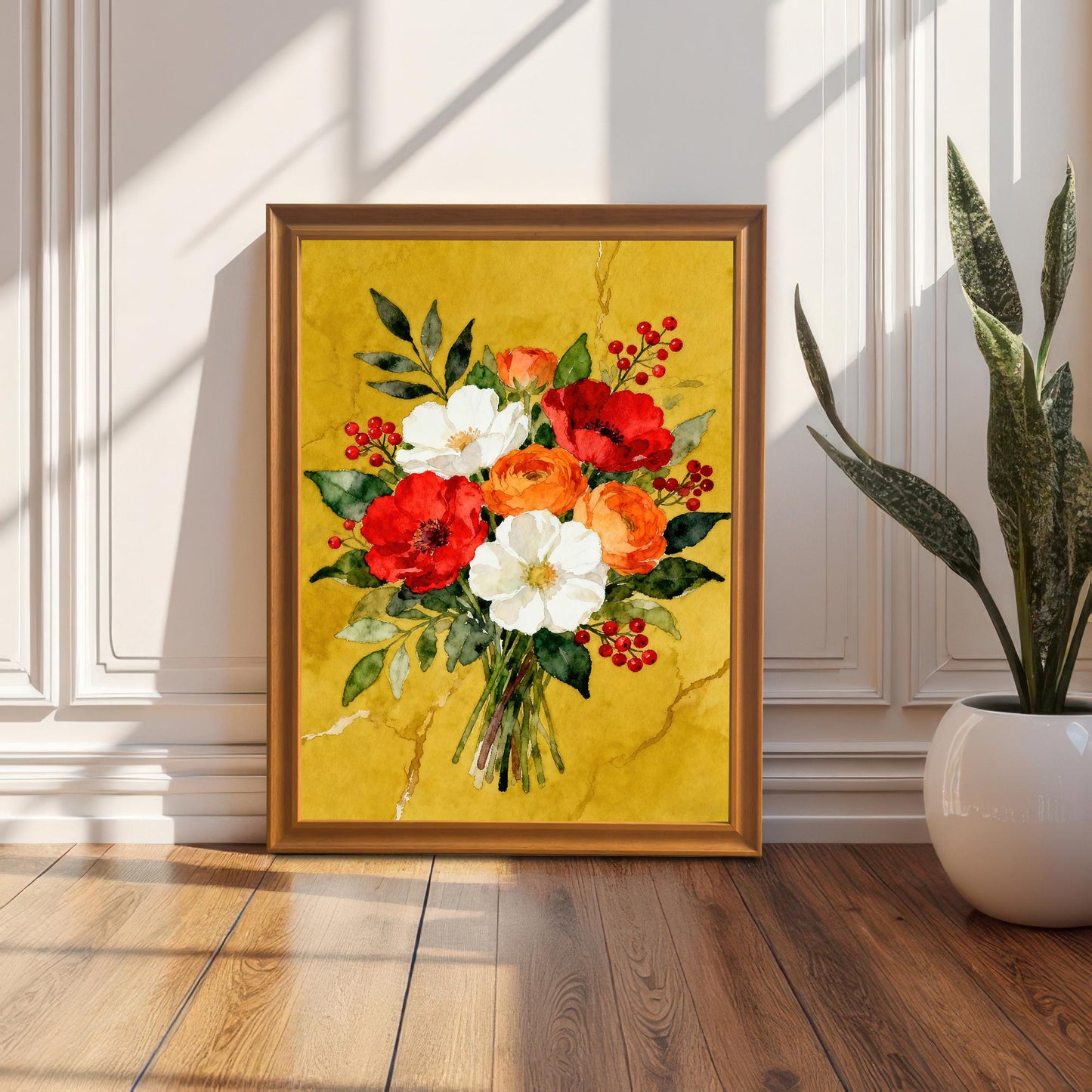 A framed watercolor print of a red, white, and orange floral bouquet in a gold frame propped on a wooden floor next to a white wainscoted wall with a houseplant to its right.