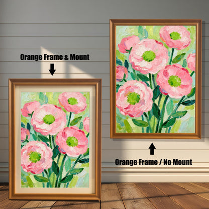 A painting of pink flowers in an orange frame, shown with and without a white mat, displayed against a rustic wood-paneled wall.
