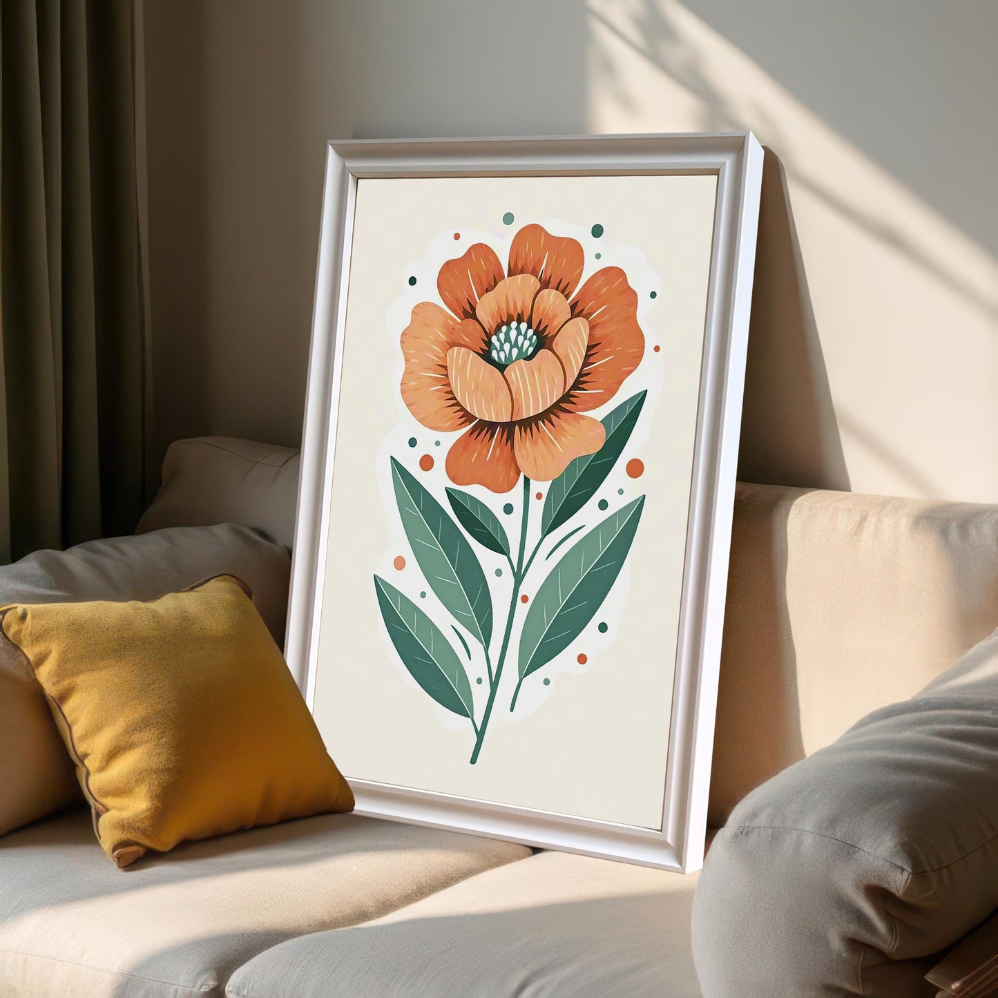 A framed print of a large orange flower with green leaves, leaning against a light-colored couch with a yellow pillow in a sunlit room.