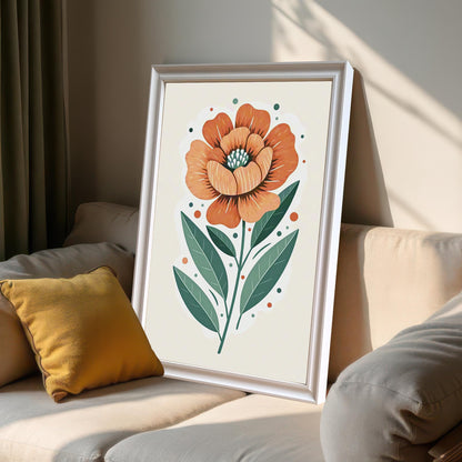 A framed print of a large orange flower with green leaves, leaning against a light-colored couch with a yellow pillow in a sunlit room.
