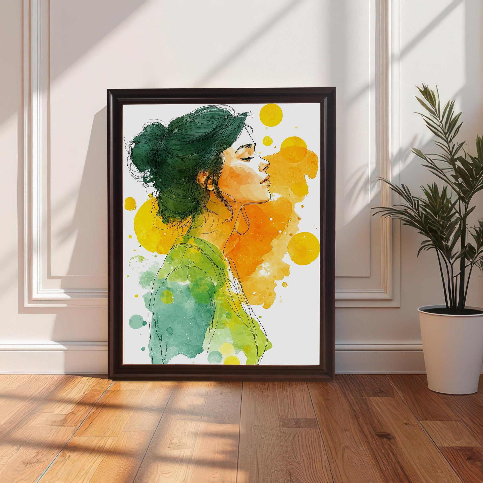 A watercolor print of a woman in a coffee-colored frame, leaning against a white wall and a white decorative wainscot. A houseplant sits to the right of the print.