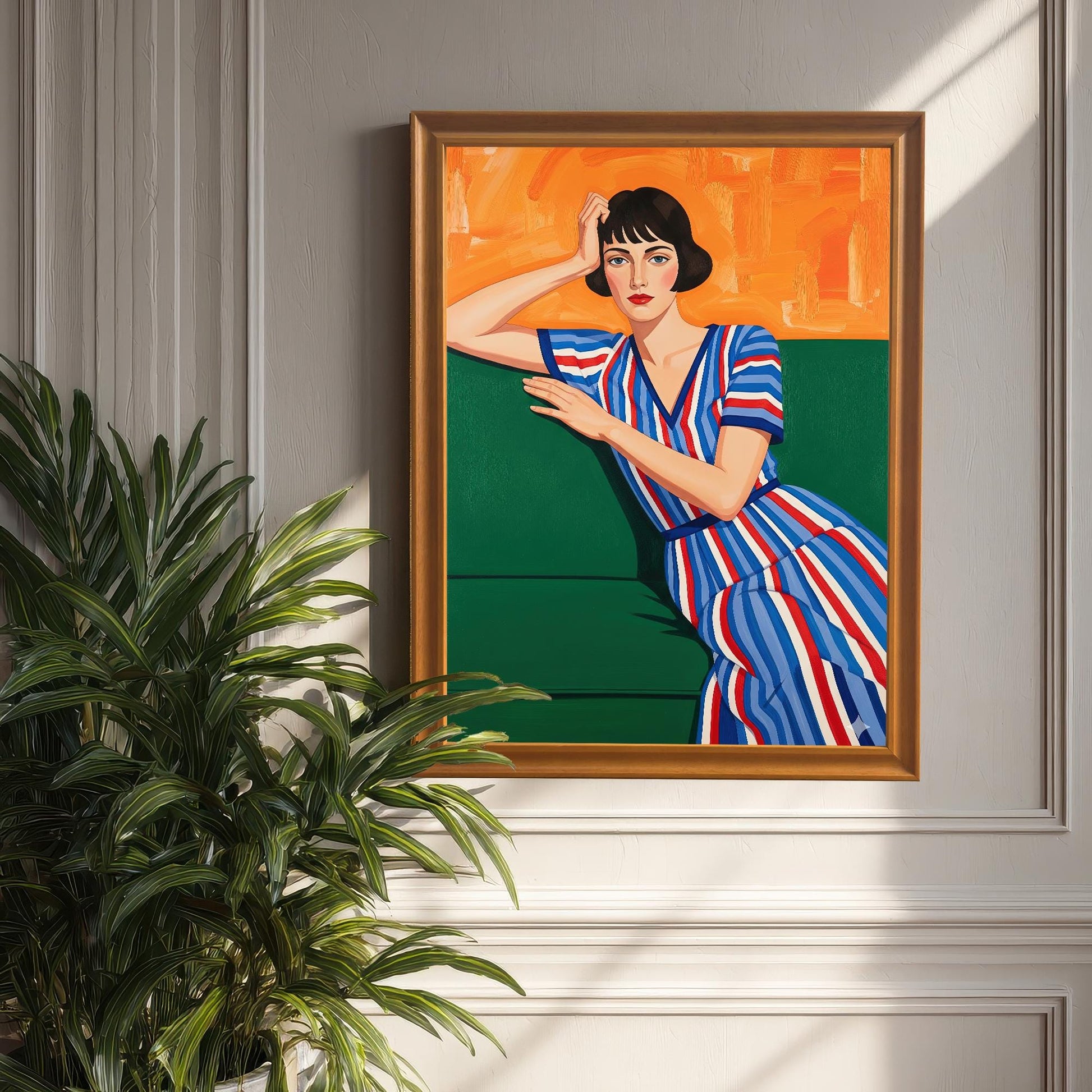 An orange-framed art print of a seated woman, propped against a white wall with wainscoting. A large, leafy houseplant is in the foreground.