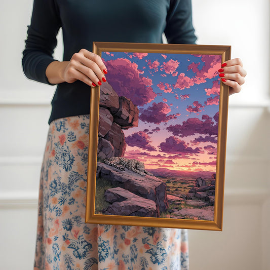 A person holding the framed sunset leopard art print with an orange/gold frame.