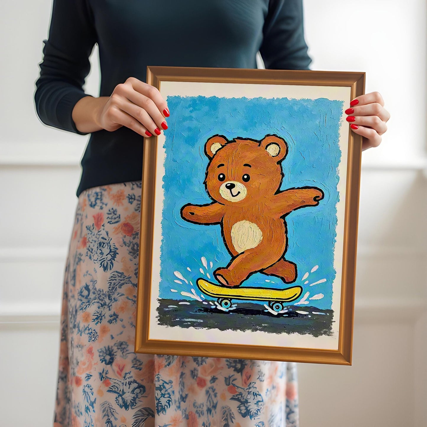 A person holds up a framed print of a brown teddy bear riding a yellow skateboard on a blue background, framed in a light brown **Orange Frame**.