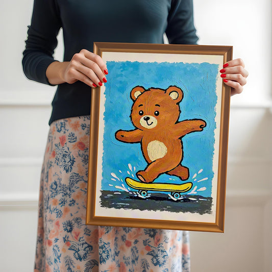 A person holds up a framed print of a brown teddy bear riding a yellow skateboard on a blue background, framed in a light brown **Orange Frame**.