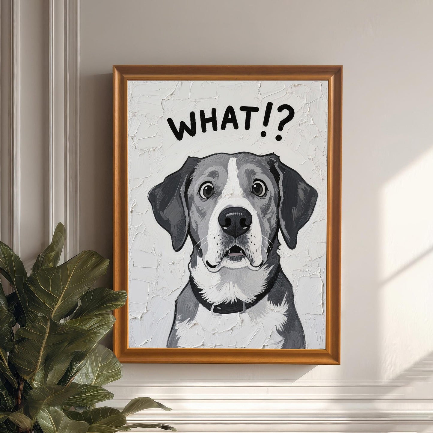 A framed art print of a surprised-looking dog with the text **WHAT!?** above its head, in an orange/wood frame, hanging on a white wall next to a large houseplant.