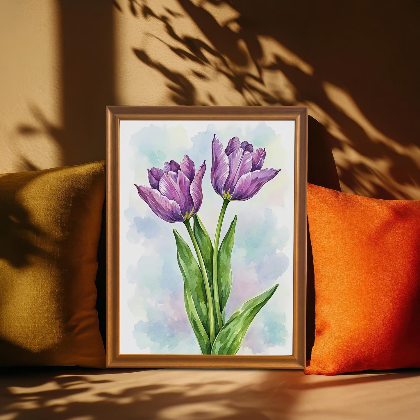 A framed painting of two purple tulips is propped up on a couch between a green and orange cushion. Sunlight shines from the right, creating shadows on a brown wall behind the painting.