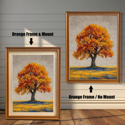 Two framed art prints of an autumn tree are on a wooden floor. The print on the left is in an orange frame with a mount, and the one on the right is in an orange frame without a mount.