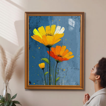 A framed painting of yellow and orange flowers on a blue background hangs on a beige wall. A woman looks at the painting, and a vase with feathery plants is on the left.