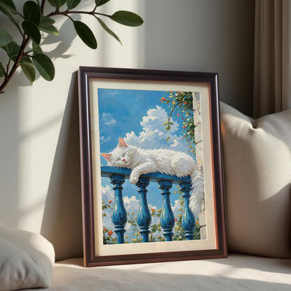 A coffee-framed art print of a white cat sleeping on a blue balcony railing, propped against pillows on a light-colored bench.