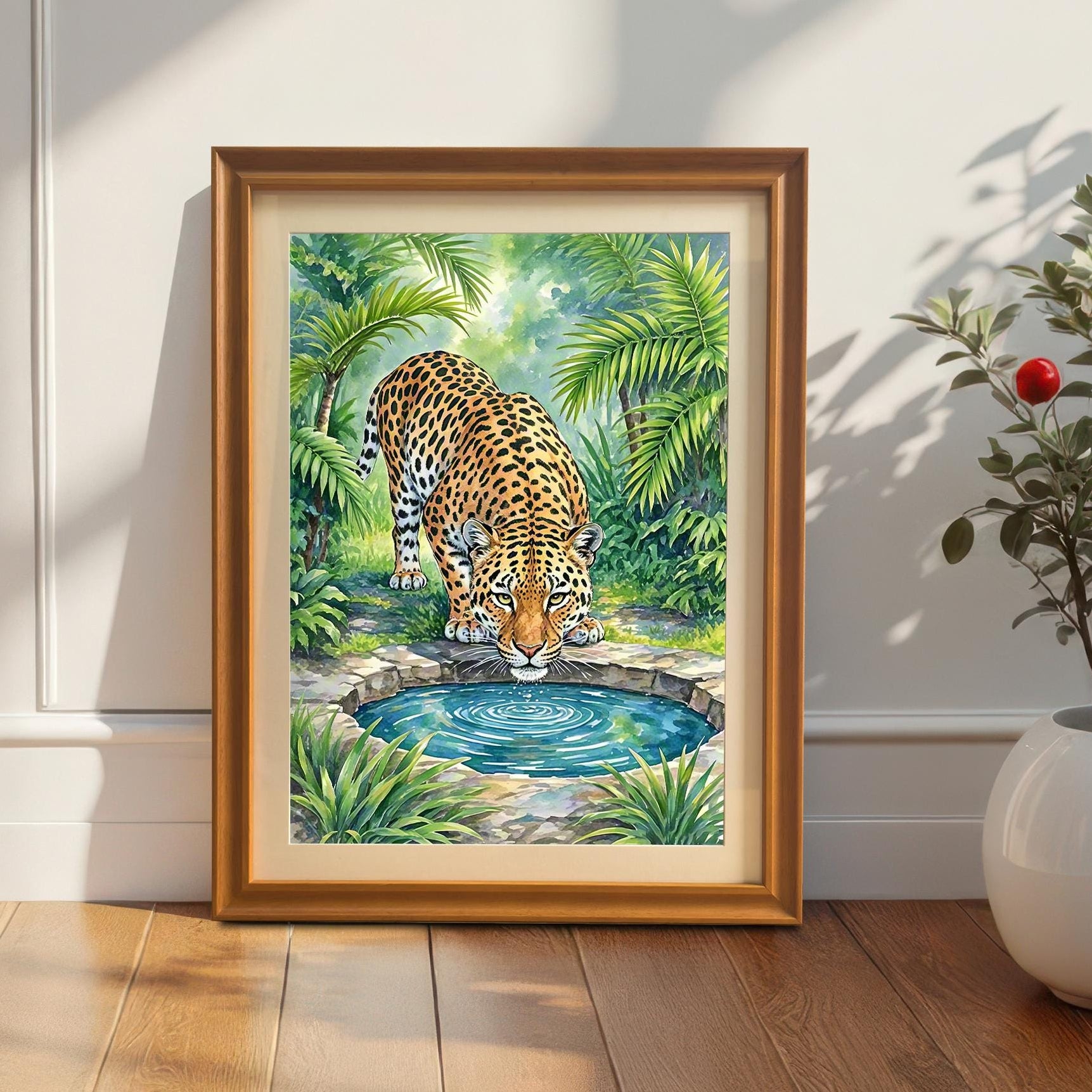 A framed painting of a leopard drinking from a pool, leaning against a white wainscot wall next to a plant in a beige pot.