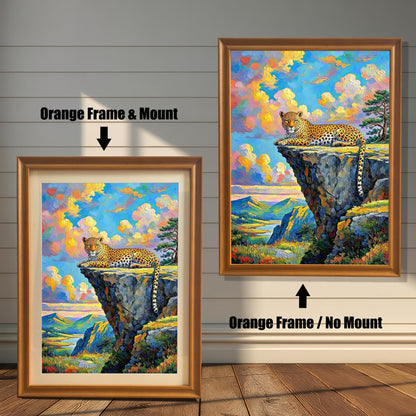 Two framed paintings of a leopard on a cliffside. The one on the left has an orange frame with a mount, and the one on the right has an orange frame with no mount.