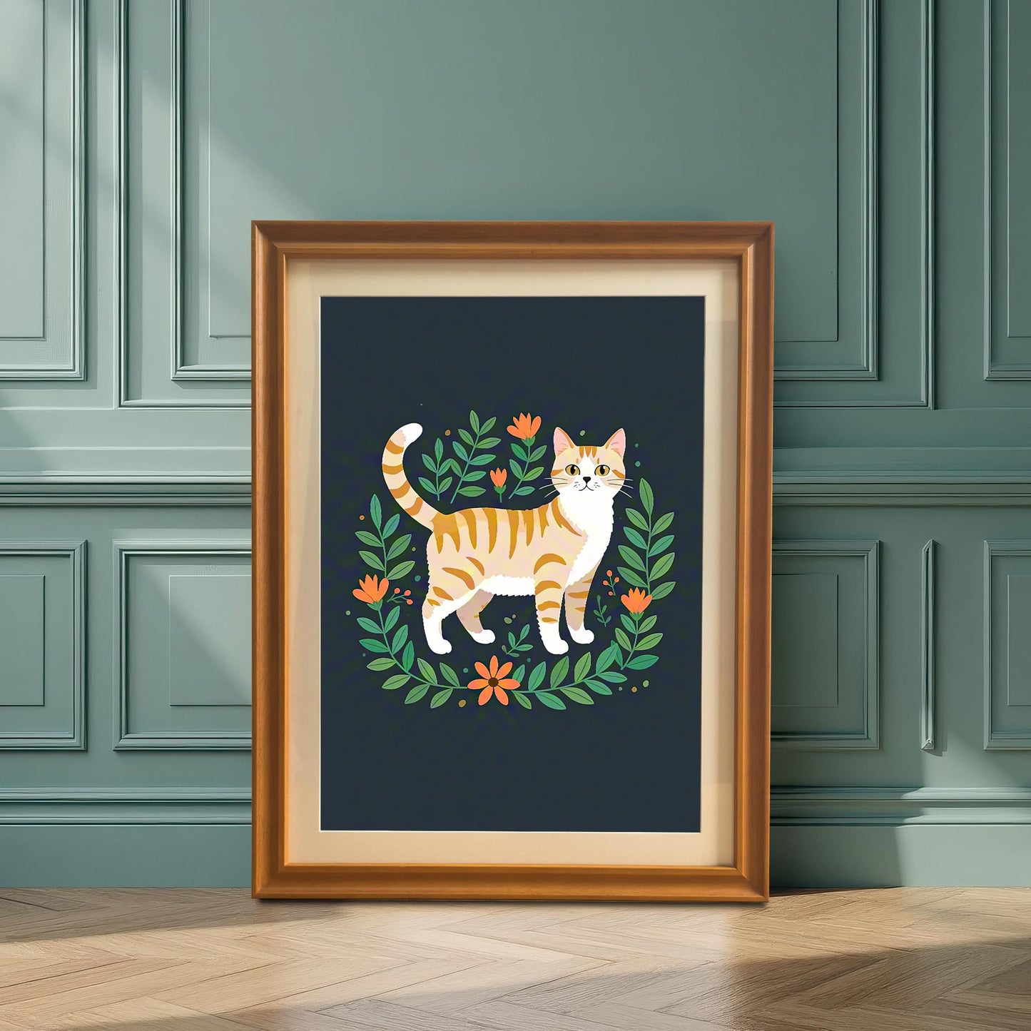 A framed art print of an orange striped cat surrounded by a floral wreath, in an orange frame, leaning against a dark teal paneled wall on a wooden floor.