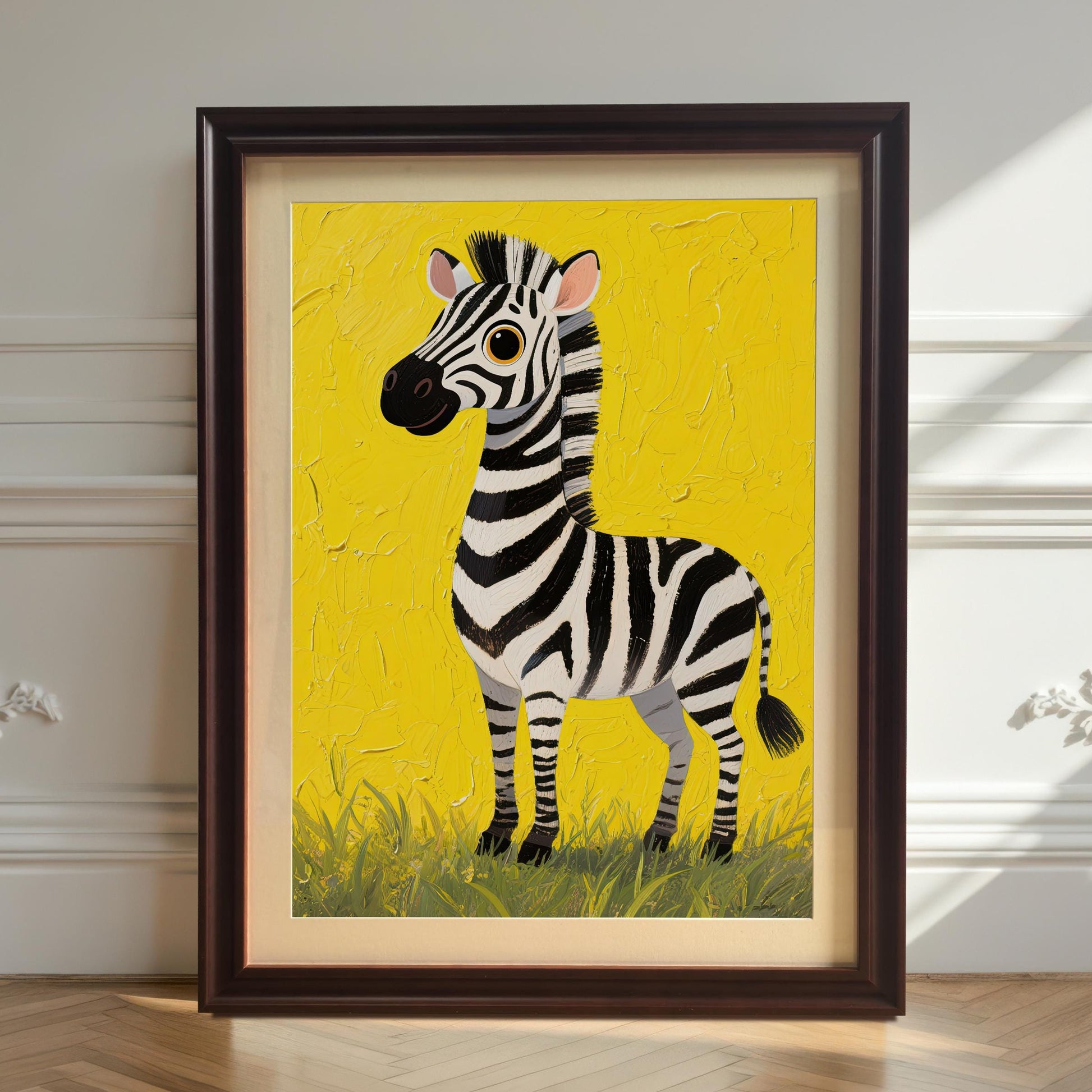 A framed zebra art print with a dark brown frame and a white mat leans against a white wainscoting wall on a light wood floor. The bright yellow background of the art stands out against the neutral wall.