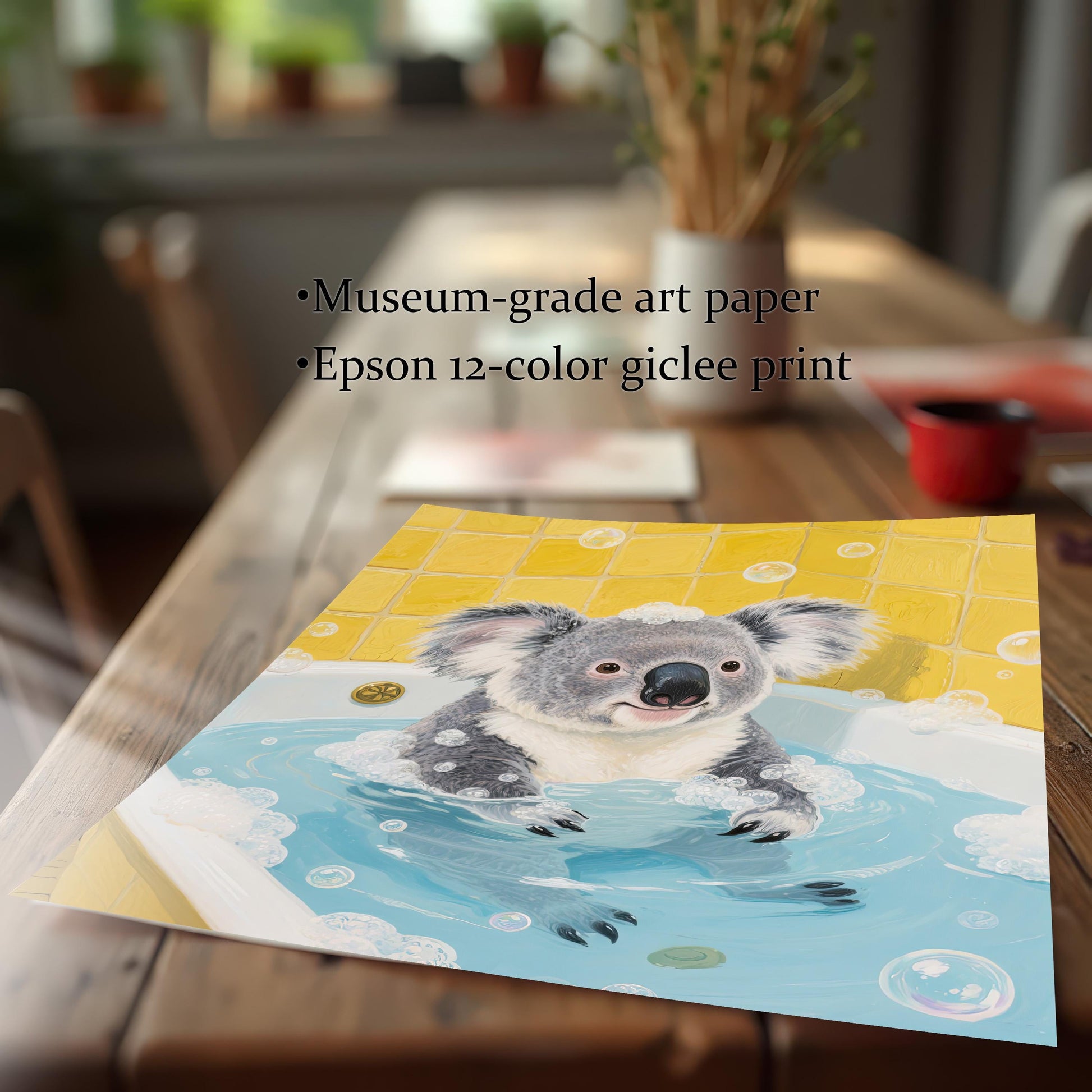 A close-up of an art print of a koala in a bathtub, lying on a wooden table. The print is slightly curved at the bottom, showcasing the paper and print quality. The background is a blurred-out indoor setting.