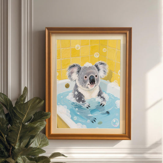 A framed print of a cute koala in a bubble bath, with a yellow-tiled background. The frame is a warm, light brown. The image is a close-up, focusing on the framed art.