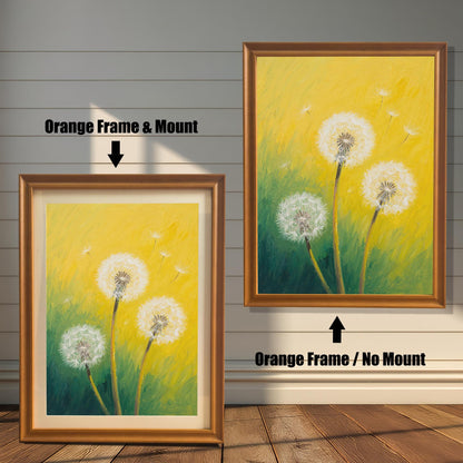 Two framed dandelion art prints on a wood paneled wall. One has an orange frame with a mount, and the other is the same frame without a mount.