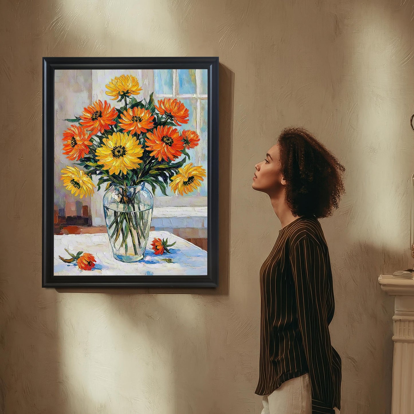 A person with curly hair stands admiring a framed print of orange and yellow flowers hanging on a textured wall.