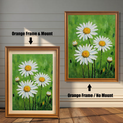 A side-by-side comparison of two framed daisy prints. The one on the left has an orange-colored frame and a cream-colored mat. The one on the right has an orange-colored frame with no mat.