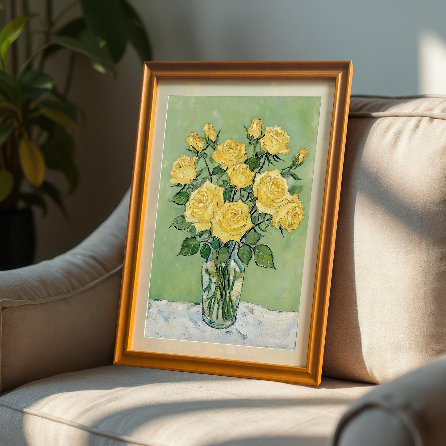 An orange-brown-framed art print of a yellow rose bouquet rests on a gray armchair.