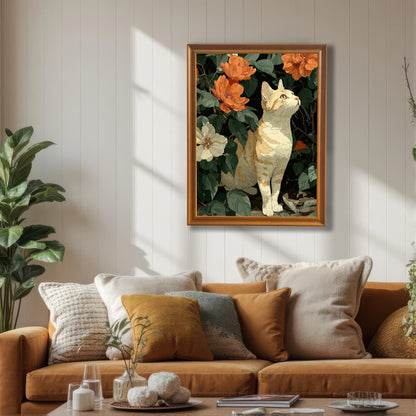 A framed wall art print of a cat among flowers, featuring an orange/wood frame, hanging above a tan sofa with warm-colored pillows in a sunlit living room.