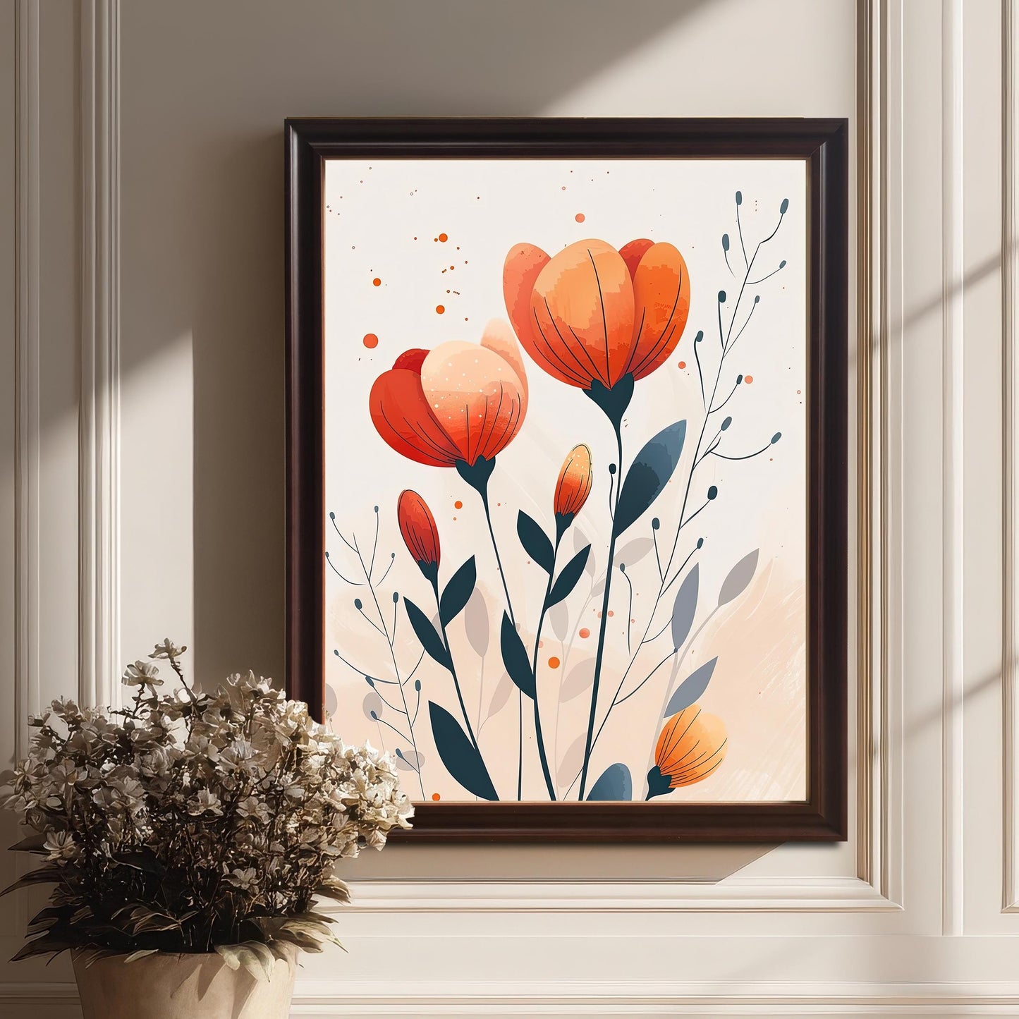 A framed art print of orange and red flowers with a subtle pink and white background. The dark brown-framed art rests on a wood floor next to a white pot with dried flowers.