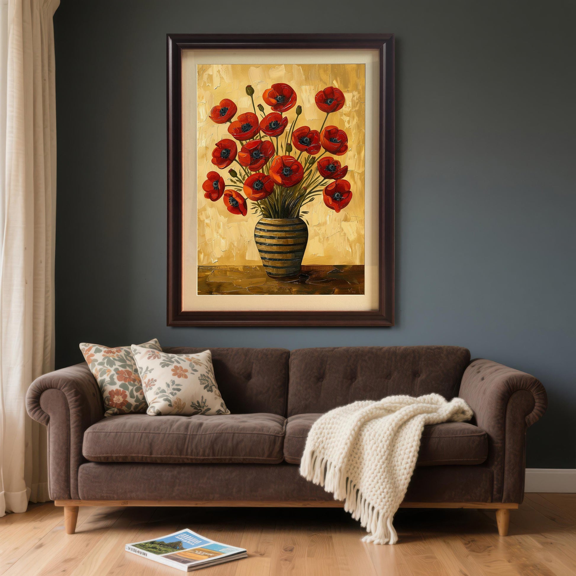 A framed art print of red poppies in a striped vase hangs on a dark gray wall above a brown couch with pillows and a blanket.