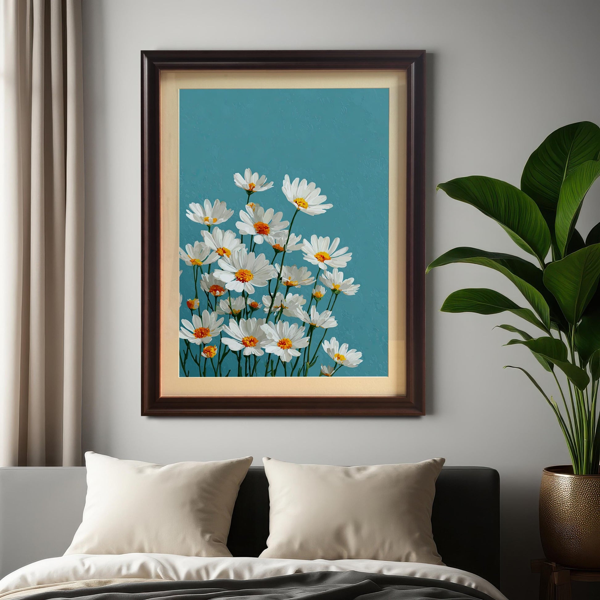 A coffee-colored framed art print of white daisies on a teal background hangs on a light gray wall above a couch with two pillows.